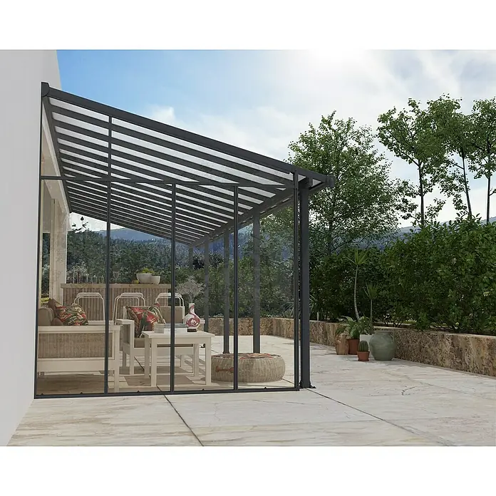 Palram – Canopia Seitenwand - Anthrazit - Dunkelgrau gerahmter Glaswintergarten überdacht eine Terrassensitzgruppe und schafft einen Wohnbereich im Freien.