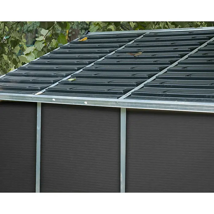Palram – Canopia Gartenhaus Rubicon - Außenmaß inkl. Dachüberstand (B x T): 237,1 x 3,03 m, Kunststoff, Grau - Dunkelgraues strukturiertes Dach und Wand eines Gartenschuppens mit silbernem Metallrahmen, umgeben von Laub.