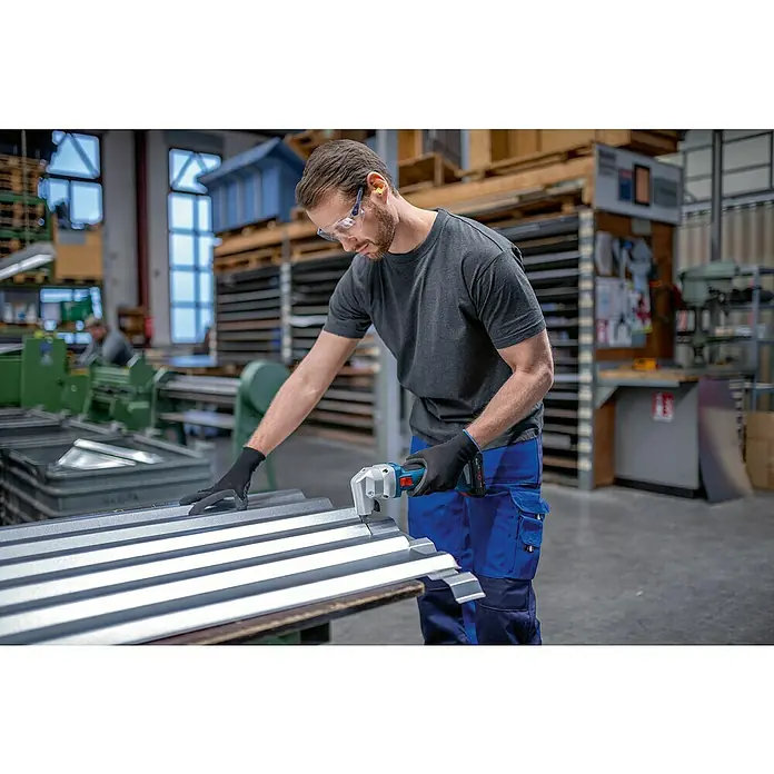 Bosch Professional AMPShare 18V Akku-Nager GNA 18V-16 E Pro Solo - 18 V, Ohne Akku, Leerlaufhubzahl: 1.400 /min - Mann in Schutzausrüstung schneidet Wellblech mit einer blau-schwarzen Akku-Blechschere.