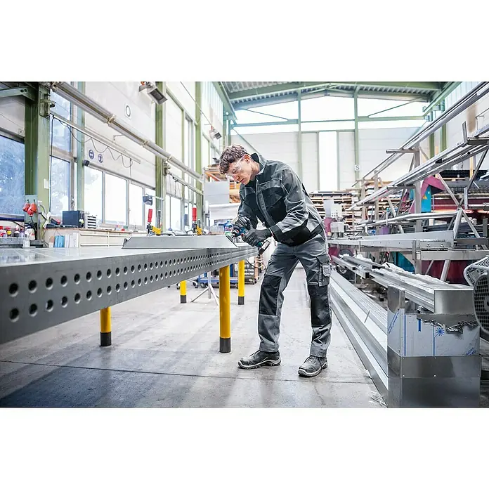 Bosch Professional Geradschleifer GWG 12V-50 S PRO SOLO - Leerlaufdrehzahl: 5.000 U/min - 15.000 U/min - Arbeiter verwendet ein blaues/schwarzes Akku-Multitool an einem Metallwerkstück.
