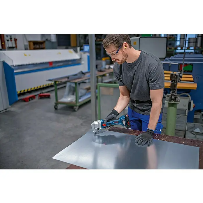 Bosch Professional Akku-Nager GNA 18V-16 E PRO - 18 V, 2 Akkus, 12 Ah - Blau-schwarze Bosch Akku-Blechschere schneidet ein Metallblech in einer Werkstatt.