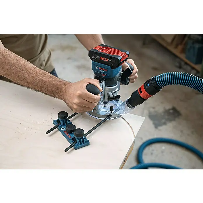 Bosch Professional AMPShare 18V Akku-Kantenfräser GKF 18V-8 PRO SOLO - 18 V, Ohne Akku, Leerlaufdrehzahl: 10.000 U/min - 30.000 U/min - Person fräst eine Kurve in Holz mit einer blauen Bosch Akku-Oberfräse, geführt von einem Zirkelanschlag, mit Staubabsaugung.
