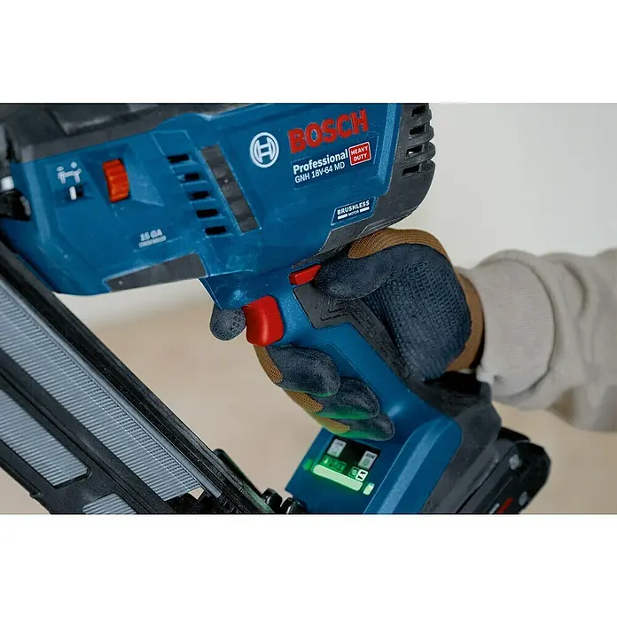 Bosch Professional Elektronagler GNH 18V-64 MD PRO SOLO - Länge Nagel: 32 mm - 64 mm, Magazinkapazität Nägel: 105 Stk. - Behandschuhte Hand hält blaues Bosch Professional Akku-Nagelgerät (GNH 18V-64 MD) mit rotem Abzug, Bedienelementen und grüner Batterieanzeige.