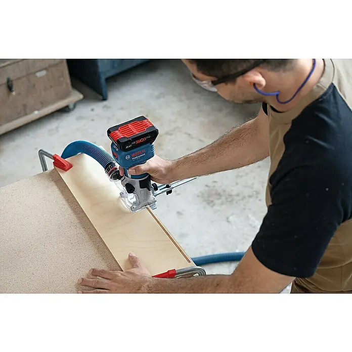 Bosch Professional AMPShare 18V Akku-Kantenfräser GLF 18V-8 PRO SOLO - 18 V, Ohne Akku, 10.000 U/min - 30.000 U/min, Inkl. L-Boxx - Person nutzt blauen Bosch Akku-Fräse mit rotem Akku zum Fräsen einer Holzplatte, angeschlossen an Staubabsaugung.