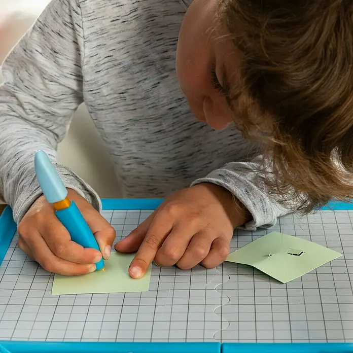 Fiskars Bastel-Set Schneidestift und -matte für Kinder - 2 -tlg. - Kind benutzt blauen Präzisionsschneider zum Papierschneiden auf einer Schneidematte.