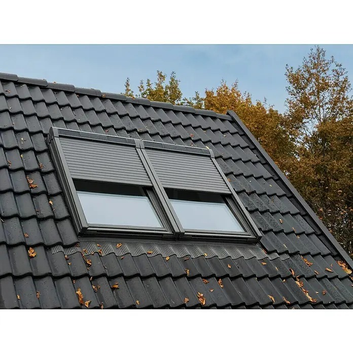 Velux Dachfenster-Rollladen Solar SSL CK06 0000K - Passend für Fenstergröße: CK06, C06, Passend für Fenstertyp: GGL, GGU, GPL, GPU, GHL, GHU, GZL, GLL, GLU, VU und VKU - Zwei dunkelgraue Dachfenster mit Außenrollläden, in ein schwarzes Ziegeldach integriert.