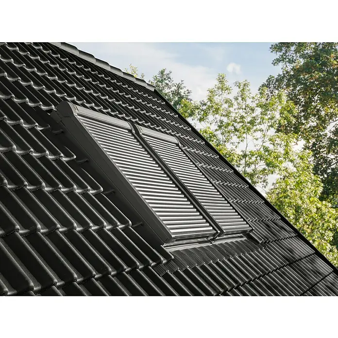 Velux Dachfenster-Rollladen Elektro SML CK06 0000K - Passend für Fenstergröße: CK06, C06, Passend für Fenstertyp: GGL, GGU, GPL, GPU, GHL, GHU, GZL, GLL, GLU, VU und VKU - Zwei dunkle Dachfenster mit silbernen Außenrollläden, auf einem schwarzen Ziegeldach montiert.