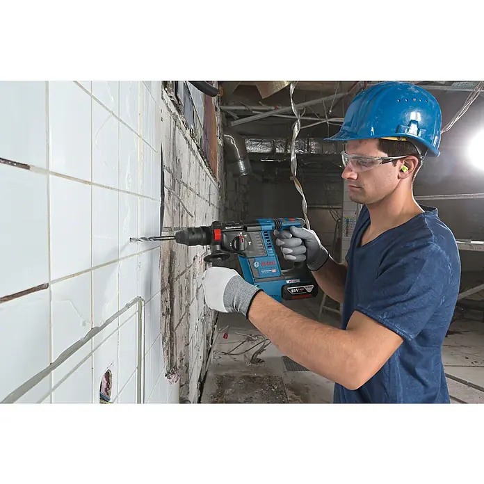 Bosch Professional AMPShare 18V Akku-Kombihammer Pro Heavy Duty GBH 18V-26F - 18 V, Ohne Akku, 2,6 J - Mann in Schutzausrüstung bohrt mit einem blau-schwarzen Bosch Bohrhammer in eine geflieste Wand.