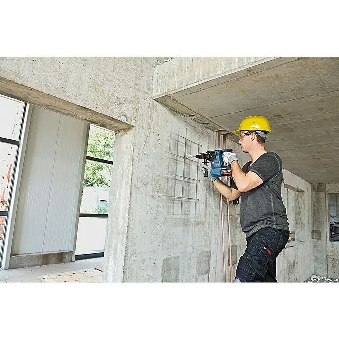 Bosch Professional AMPShare 18V Akku-Kombihammer Pro Heavy Duty GBH 18V-26F - 18 V, Ohne Akku, 2,6 J - Mann in Schutzkleidung bohrt mit blau-rotem Bosch 18V Akku-Bohrhammer in Betonwand.