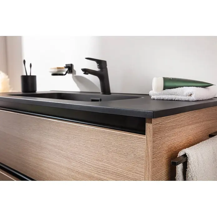 Fackelmann Vita Einbauwaschbecken - 101 x 46,5 cm, Hahnloch: Mitte, Mit Überlauf, Schwarz - Moderne schwarze integrierte Spüle und Armatur auf schwarzer Arbeitsplatte mit hellem Holzunterschrank. Badaccessoires sind sichtbar.