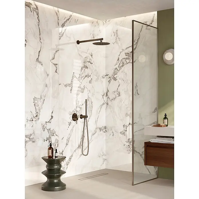 Corso Italia Feinsteinzeugfliese Lunar - 120 x 278 cm, Grau, Glänzend - Moderne Dusche mit weißen und grauen Marmorwänden, dunkelbronzenen Armaturen und einem grünen Hocker mit Toilettenartikeln.