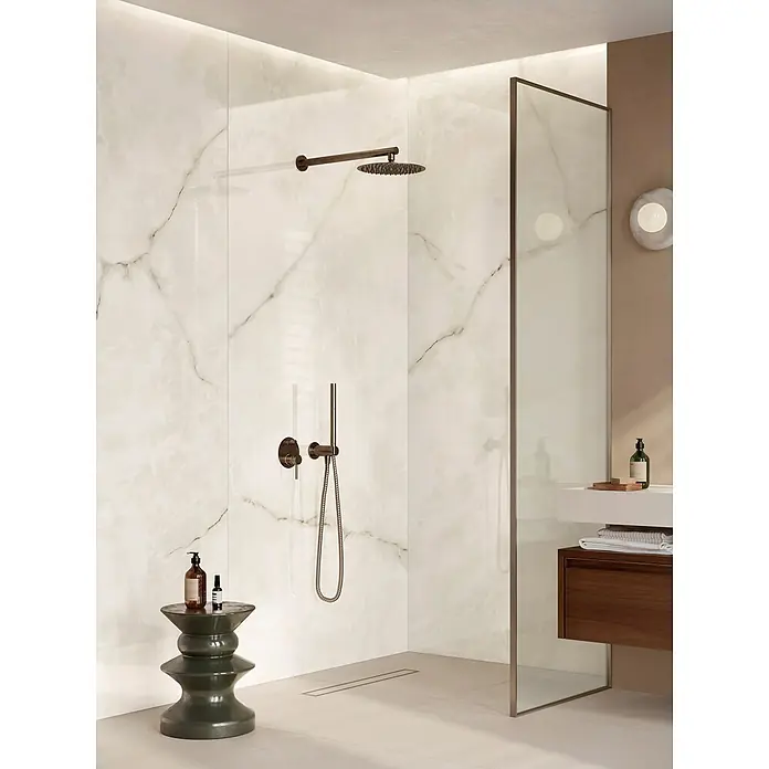 Corso Italia Feinsteinzeugfliese Onyx - 120 x 278 cm, Weiß, Glänzend - Moderne Dusche mit weißen Marmoroptikwänden, dunkelbronzener Armatur, Glasabtrennung und Linienentwässerung.