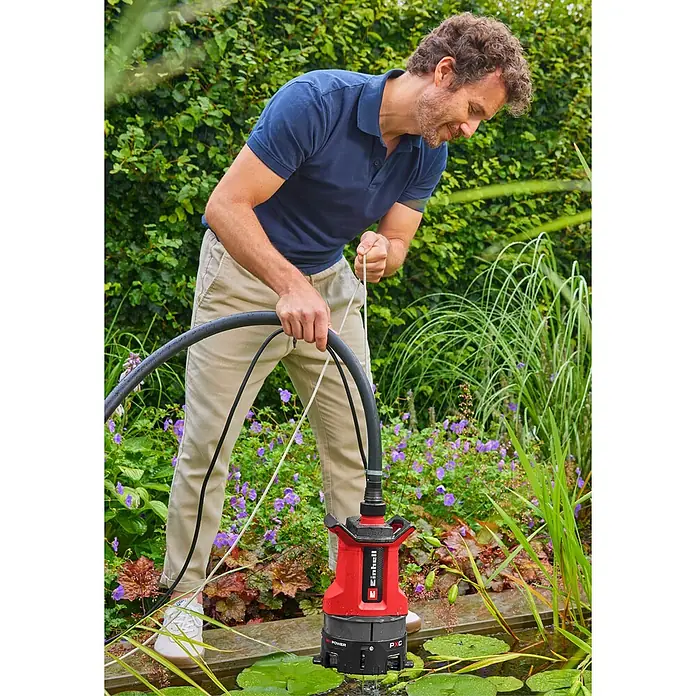 Einhell Power X-Change 18V Schmutzwasserpumpe GE-DP 36/35 LL Li-Solo - 36 V, Max. Fördermenge: 14.000 l/h - Mann setzt eine rot-schwarze Einhell Tauchpumpe in einen Gartenteich ein.