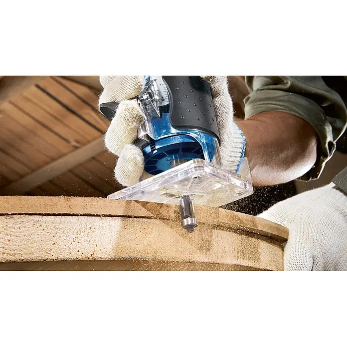 Bosch Professional Elektro-Oberfräse GLF 55-6 - 550 W, 33.000 U/min - Blauer Router mit klarer Basis bearbeitet Holz und erzeugt Sägespäne.