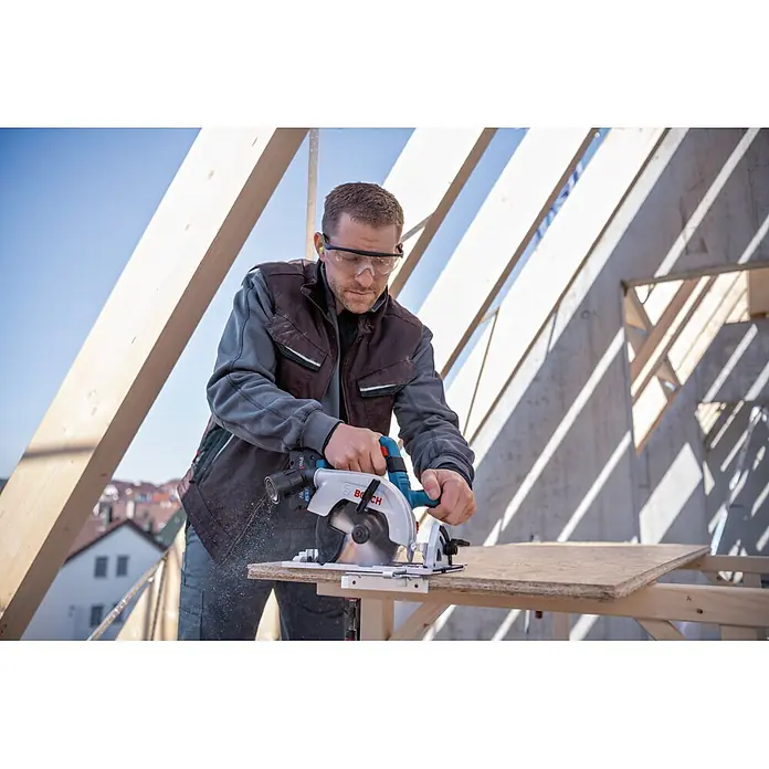 Bosch Professional Akku-Handkreissäge - 18 V, 2 Akkus, Durchmesser Sägeblatt: 165 mm, 5.000 U/min - Mann schneidet mit einer blau-silbernen Bosch Handkreissäge ein Holzbrett.