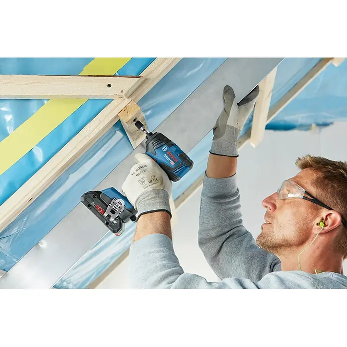 Bosch Professional AMPShare 18V Akku-Drehschlagschrauber GDR 18V-200 - 18 V, Ohne Akku, 200 Nm, Karton - Blauer und schwarzer Bosch-Schlagschrauber, der von einer Person verwendet wird, um Material in einer Baustellenumgebung zu befestigen.