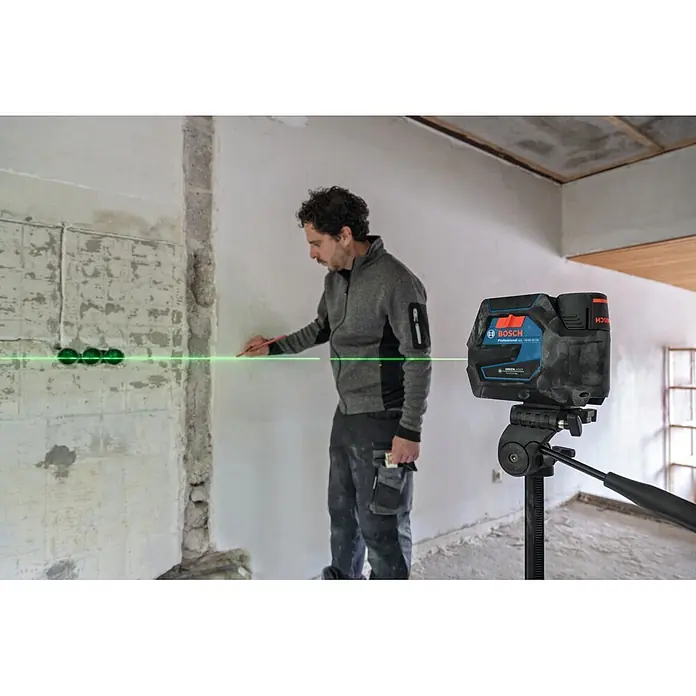 Bosch Professional Kreuzlinienlaser GCL 12V-50-22 CG PRO - 12 V, 1 Akku, Max. Arbeitsbereich: 25 m - Ein Mann benutzt ein blau-schwarzes Bosch Professional Laser-Nivelliergerät, um eine grüne Linie an einer Wand zu markieren.
