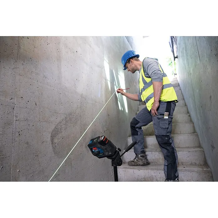 Bosch Professional Kreuzlinienlaser GCL 12V-50-22 CG PRO - 12 V, 1 Akku, Max. Arbeitsbereich: 25 m - Ein Arbeiter nutzt ein Bosch Laser-Nivelliergerät auf einem Stativ, um eine grüne Linie zum Markieren einer Betonwand zu projizieren.