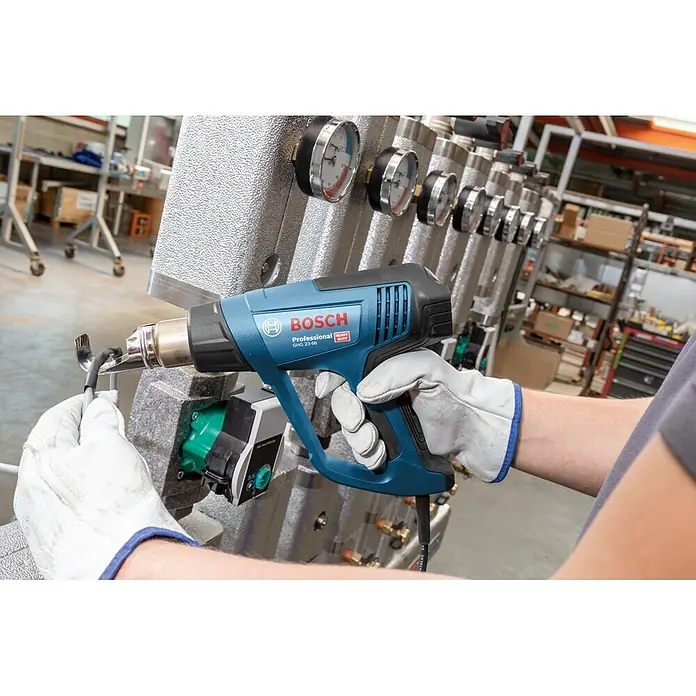 Bosch Professional Heißluftgebläse GHG 23-66 PR - Temperaturbereich: 50 °C - 650 °C - Blaue und schwarze Bosch Professional Heißluftpistole GHG 23-66 wird von behandschuhten Händen zum Erhitzen eines Kabels verwendet.