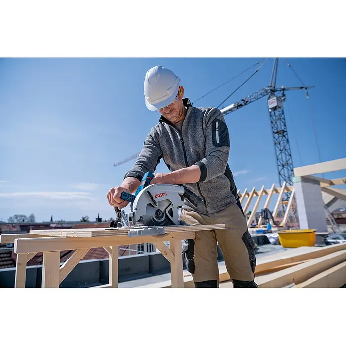 Bosch Professional AMPShare 18V Akku-Handkreissäge GKS 18V-70 L PRO - 18 V, 2 Akkus, Durchmesser Sägeblatt: 190 mm, 5.000 U/min - Ein Arbeiter schneidet Holz mit einer grau-blauen Bosch Handkreissäge auf einer Baustelle.