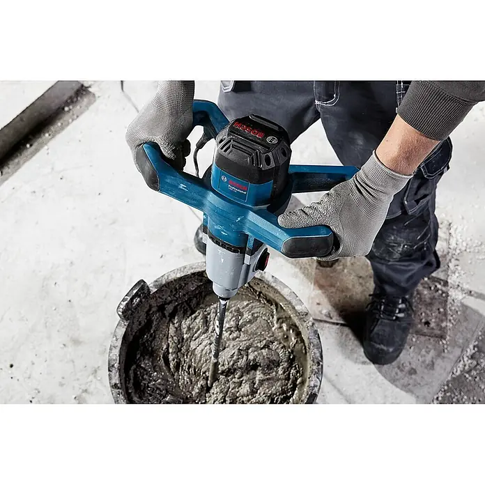 Bosch Professional Rührwerk GRW 140 - 1.400 W - Eine Person mischt mit einem blau-schwarzen Bosch Professional Rührgerät grauen Mörtel in einem Eimer, graue Handschuhe tragend.