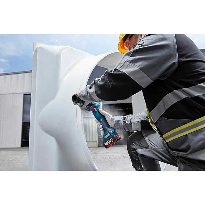 Bosch Professional AMPShare 18V Akku-Winkelschleifer GWS 18V-11 S PRO - Ohne Akku, Durchmesser Scheibe: 125 mm - Person in Schutzkleidung bearbeitet ein weißes Objekt mit einem blau-schwarzen Bosch Akku-Trennschleifer.