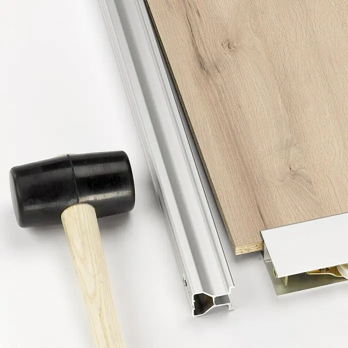 Room Plaza Easy Schiebetür-Bau-Set - Buche Naturwuchs/Ahorn Naturwuchs, Farbe Beschlag: Silber - Eine Nahaufnahme von einer Gummipfeife und einer Metallleiste, die verwendet werden, um einen Laminatboden zu verlegen.