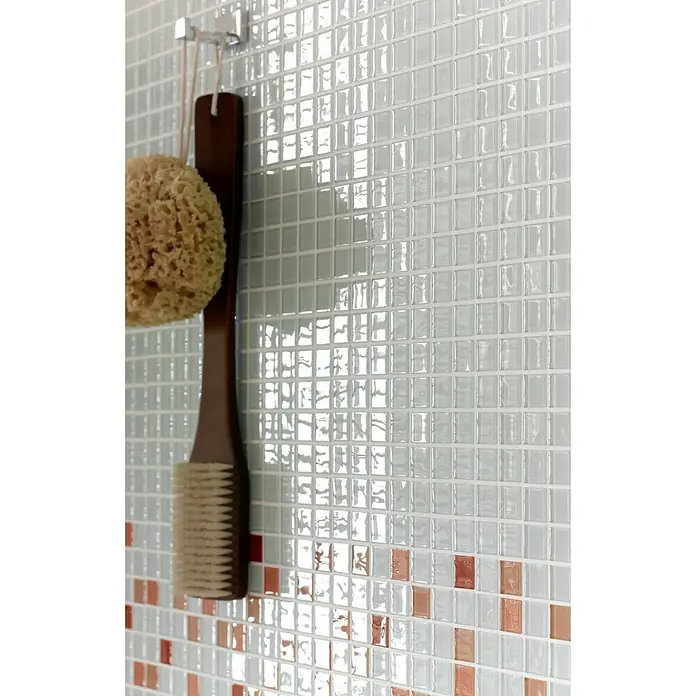 Mosaikfliese Quadrat Crystal Uni CM 4040 - 32,7 x 30,2 cm, Weiß, Glänzend - Nahaufnahme einer Badezimmerwand mit hellblauen und kupferfarbenen Mosaikfliesen, einem Schwamm und einer Bürste, die an einem Haken hängen.