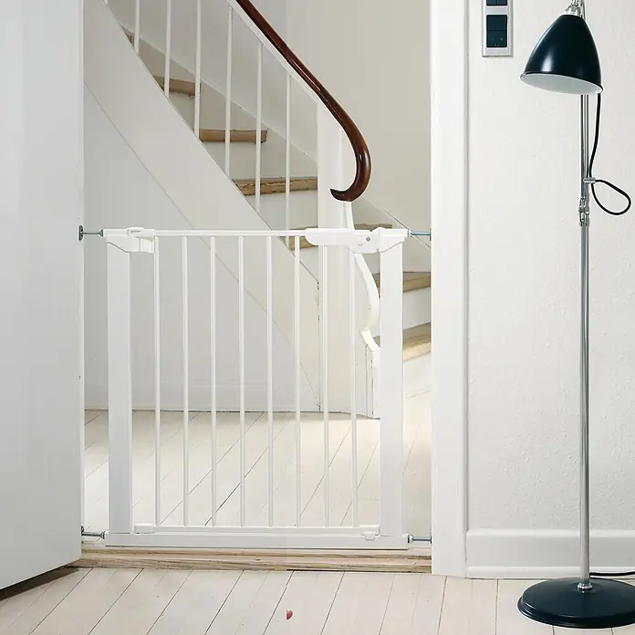 Dolle Sicherheitsgitter Björn - Höhe: 73 cm, Weiß - Weißes Metall-Babygitter am Fuß einer hellen Treppe installiert.