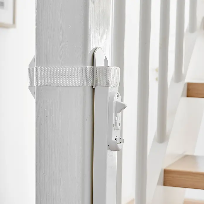 Dolle Sicherheitsgitter Adapter - Weiß - Weiße Treppenschutzgitterbefestigung mit Riegel an Holzpfosten mit Gurt, neben einer Treppe.