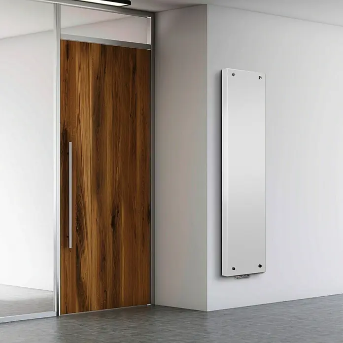 Camargue Designheizkörper Vitromit - B x H: 500 x 1.500 mm - Ein modernes Interieur mit einer schlanken, weißen Infrarotheizung an einer weißen Wand neben einer Holztür.