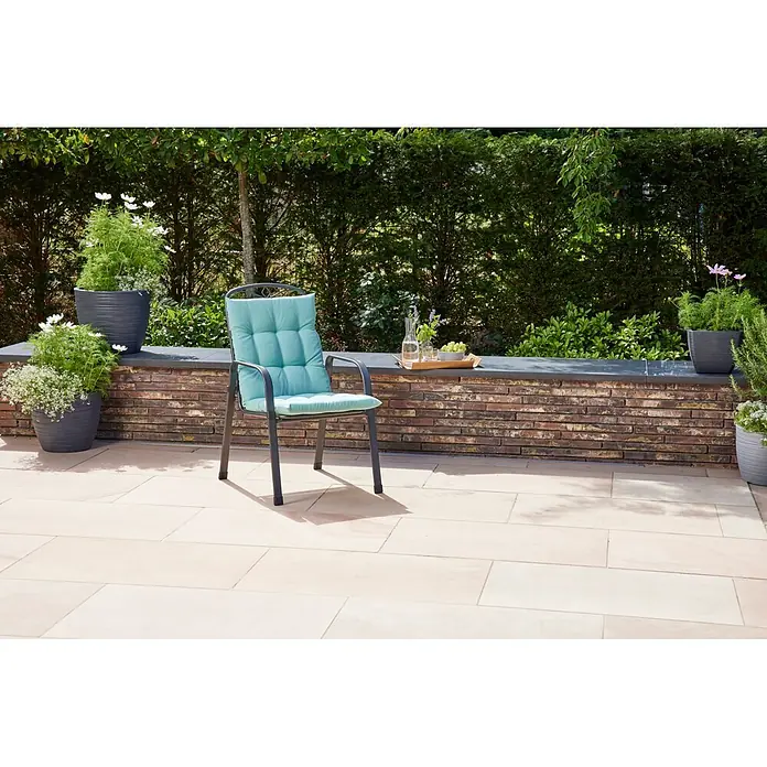 Siena Garden Atria Sitzauflage - L x B x H: 100 x 48 x 8 cm, Wasabi, Polyester, 1 Stk. - Dunkelgrauer Gartenstuhl aus Metall mit hellblauem Kissen auf einer Terrasse in einer üppigen Gartenumgebung.