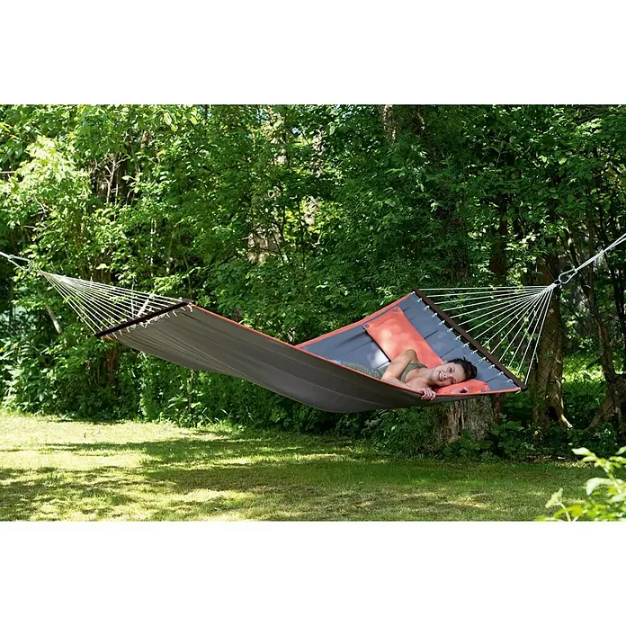Amazonas Stabhängematte American Dream - L x B: 335 x 120 cm, Grau - Frau entspannt sich in einer Hängematte im Garten, umgeben von Grün. Die Hängematte ist zwischen zwei Bäumen befestigt.