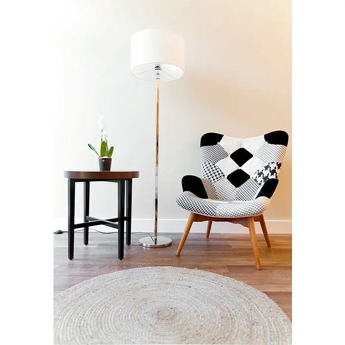 Alfombra de yute Nazar - Beige, Diámetro: 100 cm - Un rincón de lectura acogedor con un llamativo sillón patchwork, lámpara de pie, mesa auxiliar con orquídea y alfombra redonda de mimbre.