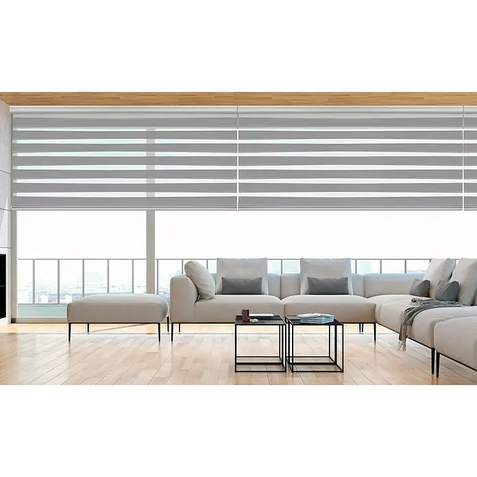 Estor noche y día Platinum - An x Al: 200 x 250 cm, Plateado - Un lujoso salón con un elegante sofá seccional beige y modernos estores enrollables dobles que brindan privacidad y un elegante control de la luz.