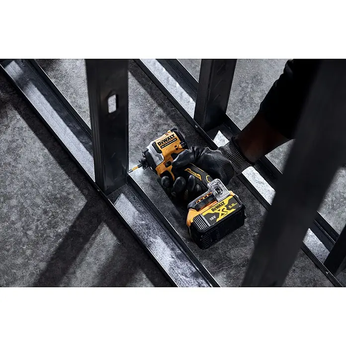 DeWalt XR 18V Atornillador de impacto de batería - 18 V, Sin batería, 205 Nm - Taladro percutor DeWalt amarillo y negro, sujetado por una mano enguantada, usado en un marco metálico.