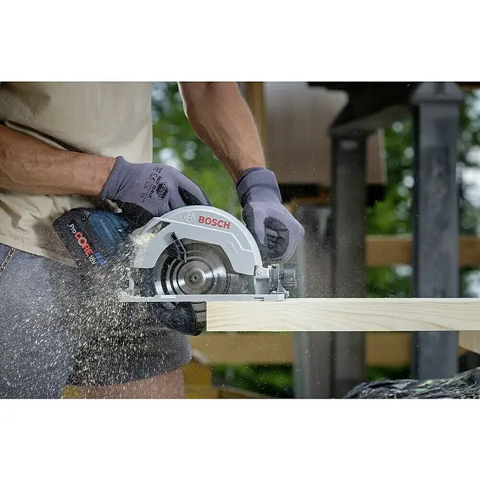 Bosch Professional AMPShare 18V Akku-Handkreissäge GKS 18V-57 G L-Boxx - 18 V, Ohne Akku, Leerlaufdrehzahl: 3.400 U/min, Sägeblatt: 165 mm - Ein Mann sägt ein Holzbrett mit einer Bosch Akku-Kreissäge ProCORE 18V, wobei Sägespäne fliegen. Professionelles Werkzeug im Einsatz.