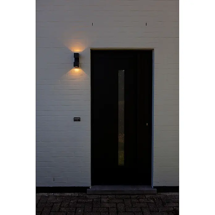 Lutec Aplique para exterior LED Fari - 10 W, L x An x Al: 92 x 65 x 193 mm, Gris oscuro, Aluminio, IP54 - Lámpara de pared exterior rectangular negra iluminando una pared de ladrillo blanca.