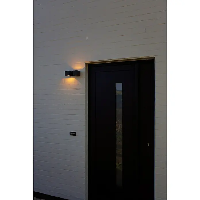 Lutec Aplique para exterior LED Fari - 10 W, L x An x Al: 92 x 65 x 193 mm, Gris oscuro, Aluminio, IP54 - Puerta de entrada moderna gris oscuro con ventana vertical, luz de pared iluminada y timbre en una pared de ladrillo claro.
