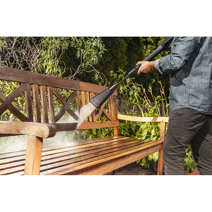 Kärcher Strahlrohr eco!Booster 120 - Passend für: Kärcher Hochdruckreiniger K 2 und K 3, 452 x 104 x 42 mm - Schwarzer Hochdruckreiniger säubert eine Holzbank; eine Hälfte ist sauber, die andere noch schmutzig.