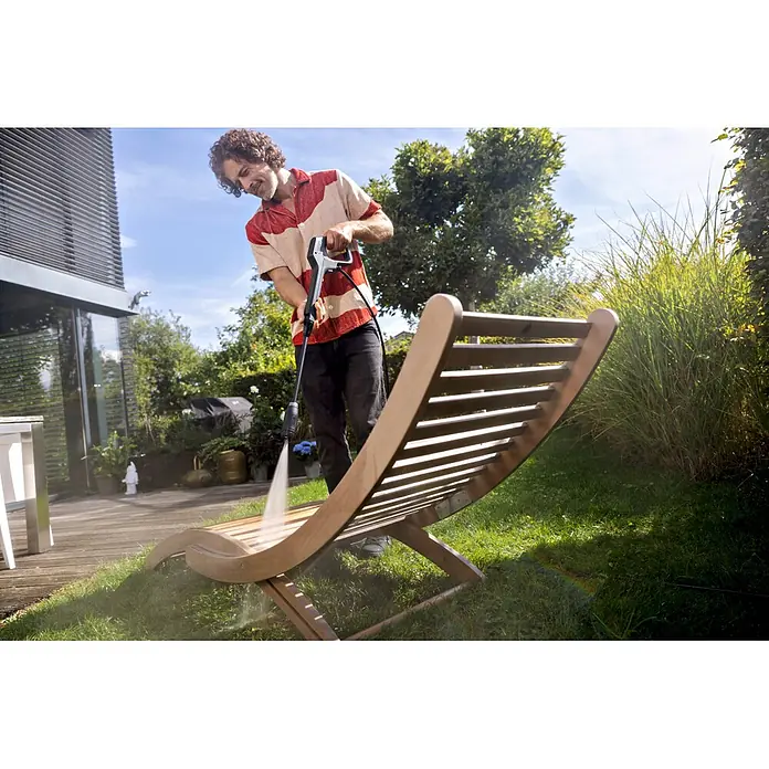 Kärcher Strahlrohr VP 135 Vario Power Jet - Passend für: Kärcher Hochdruckreiniger K 2 bis K 3 - Mann reinigt eine hölzerne Gartenliege mit einem grau-schwarzen Hochdruckreiniger, um Schmutz von den Latten zu entfernen.