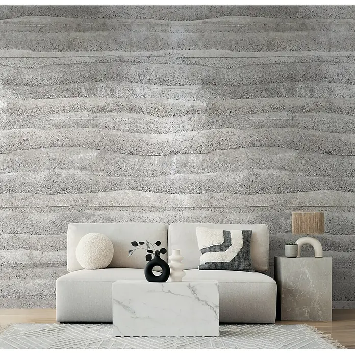 A.S. Création Metropolitan Stories Vibes & Styles Fototapete Beton I - B x H: 1,59 x 2,8 m, Vlies - Heller Stoffsofa in Grau mit weißem Marmor-Couchtisch und grauem Marmor-Beistelltisch in einem modernen Wohnzimmer.