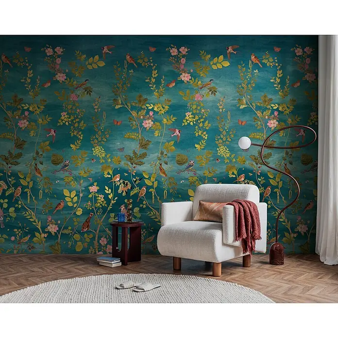 A.S. Création Metropolitan Stories Vibes & Styles Fototapete Blüte - B x H: 1,59 x 2,8 m, Vlies - Weißer Polstersessel mit Holzbeinen, darauf eine rostfarbene Decke und Kissen, in einem farbenfrohen Raum.