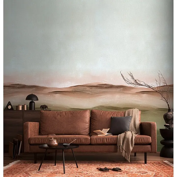 A.S. Création Metropolitan Stories Vibes & Styles Fototapete Horizont I - B x H: 1,59 x 2,8 m, Vlies - Braunes Ledersofa in einem Wohnzimmer mit einem dunklen Kissen, einem gemütlichen Überwurf und einem aufgeschlagenen Buch.