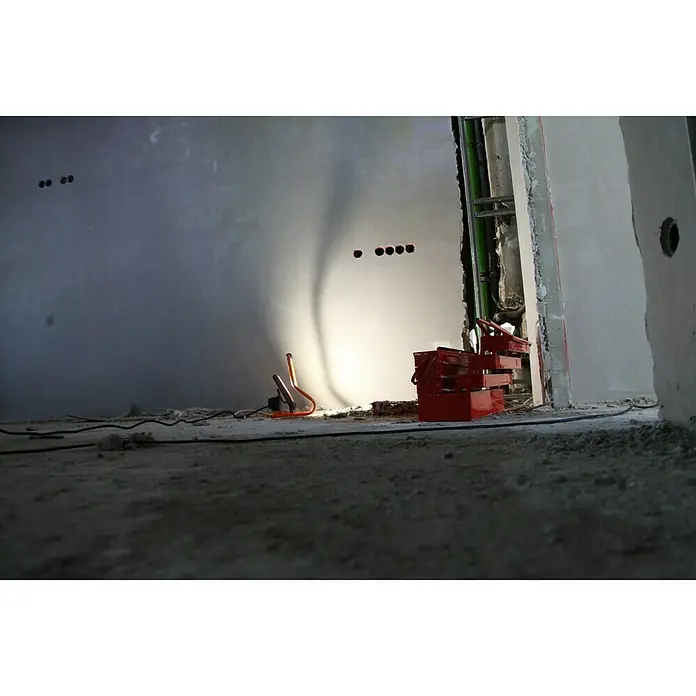 Ledvance LED-Strahler - 30 W, 2.700 lm, 4.000 K, L x B x H: 19 x 22 x 29 cm, IP44 - Aufnahme eines Arbeitsplatzes mit Werkzeugkasten und Baustellenlampe in einem Rohbau.