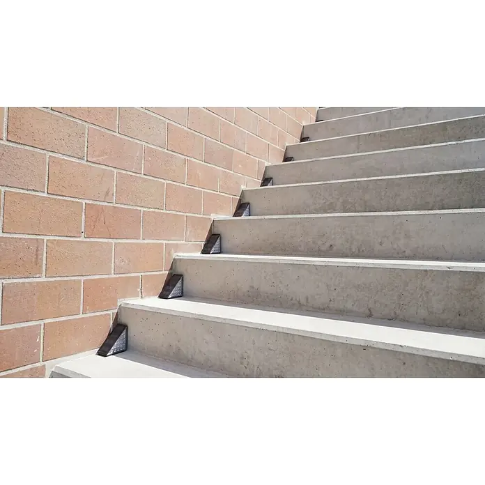 BAUHAUS Solarleuchten-Set Treppenlicht - L x B x H: 9 cm x 9 cm x 4,8 m, Schwarz, IP54, 8 lm - Dreieckige Solar-Stufenleuchten säumen Betontreppen neben einer Ziegelwand.