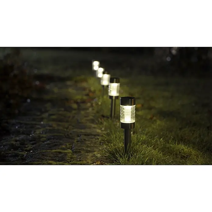 BAUHAUS Solar-Erdspieß - 0,06 W, Höhe: 39 cm, Silber, IP44, 3 lm - Solarpfadlichter mit schwarzen Köpfen und klaren Körpern beleuchten einen Weg im Gras bei Nacht.