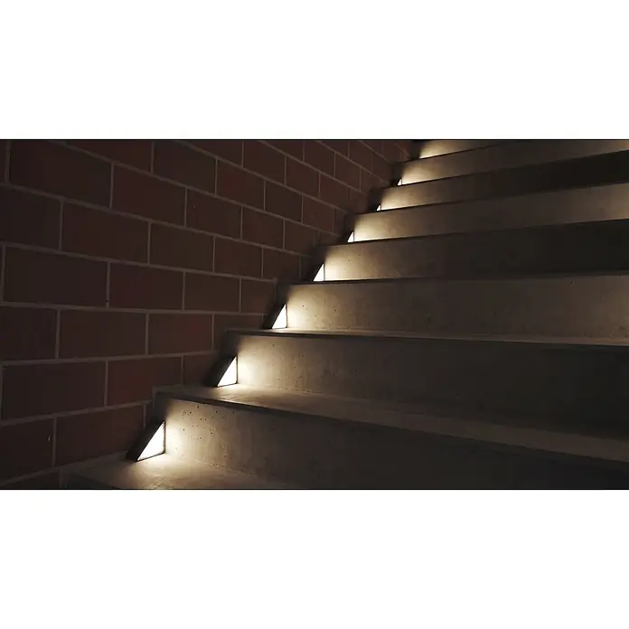 BAUHAUS Solarleuchten-Set Treppenlicht - L x B x H: 9 cm x 9 cm x 4,8 m, Schwarz, IP54, 8 lm - Betontreppe mit dreieckigen Stufenleuchten, die jede Stufe erhellen, vor einer Ziegelwand.