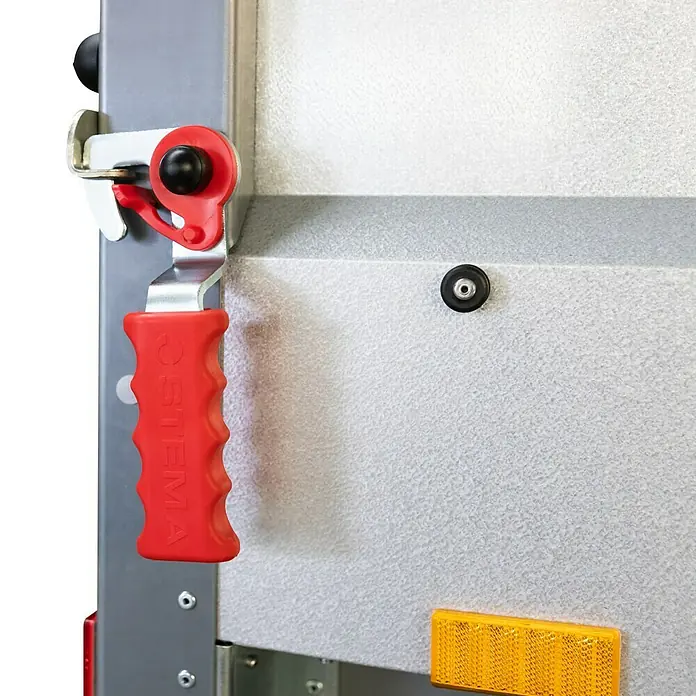 Stema Anhänger BASIC ST 2000-30-15.2 - Nutzlast: 1.575 kg, Doppelachser, Kasteninnenmaß: 301 x 153 x 35 cm, Gebremst - Nahaufnahme eines Anhängers mit einem roten OSTEMA-Griff. Der Griff ist an einem Metallrahmen befestigt und dient zum Öffnen und Schließen der Anhängertür.