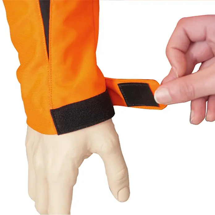 Oregon Chaqueta de trabajo Yukon - XXXL, Naranja/Gris - Puño de prenda naranja con cierre de velcro negro ajustable, asegurado por una mano.
